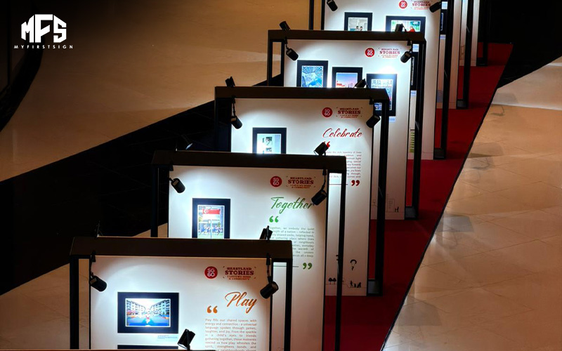 A series of illuminated Heartland Stories display panels arranged in a row along a red carpet in a large hall.